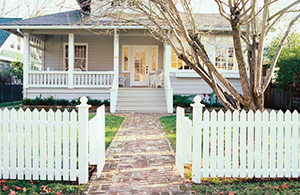 front of a home with a white picket fence