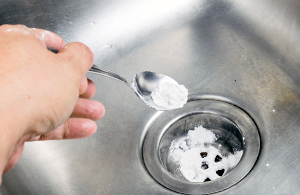 User putting baking soda in drain