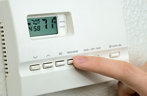 Person adjusting their thermostat